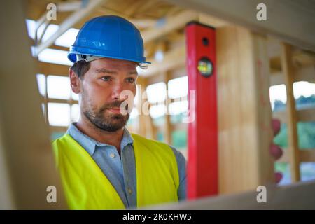 Zimmermann überprüft Holzbretter mit Wasserwaage, diy umweltfreundliche Häuser Konzept. Stockfoto