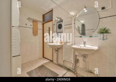 Waschbecken mit Spiegel und Dusche im modernen Badezimmer mit weiß gefliesten Wänden Stockfoto