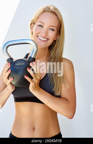 Der beste Weg, um fest und fit zu werden. Beschnittenes Porträt einer jungen Frau mit einer Kesselglocke. Stockfoto