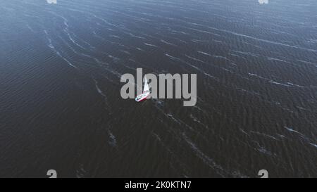 Blick von oben, Luftaufnahme des weißen, modernen, nicht großen Segelbootes oder der Yacht mit Segel Stockfoto