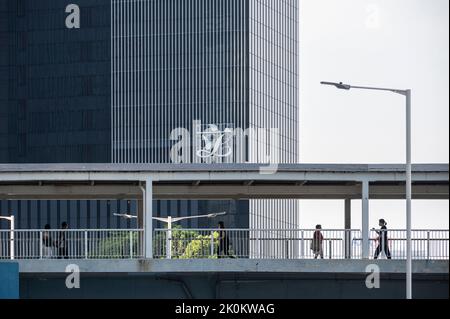 Hongkong, China. 12. September 2022. Pendler gehen durch eine Fußgängerbrücke, während der Legislative Council Complex (LegCo Complex) im Hintergrund in Hongkong zu sehen ist. (Foto von Miguel Candela/SOPA Images/Sipa USA) Quelle: SIPA USA/Alamy Live News Stockfoto