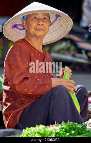 Vietnamesischer Anbieter mit Bambushut, der auf dem Straßenmarkt unter freiem Himmel, Hai Phong, Vietnam, arbeitet Stockfoto