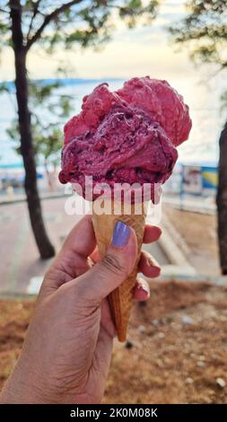 Eis-Eis-Kegel gehalten, um die heiße Sommerstadt. Womans Hand. Stockfoto