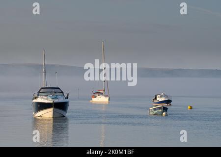 Am frühen Morgen ist Nebel und Freizeitboote im Hafen von Poole verankert Stockfoto