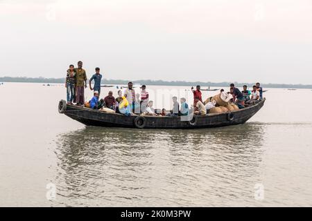 Personentransport auf Booten über den Fluss in der Nähe von Shyamnagar. Die Menschen in den kleinen Siedlungen entlang der Flüsse im Süden Bangladeschs spüren deutlich die Auswirkungen des Klimawandels. Der Meeresspiegel steigt und Dämme werden zerstört. Dadurch werden Felder und wichtige Süßwasserteiche überflutet und salzt. Daher werden große Anstrengungen unternommen, um die Banken zu stärken. Auch Wohngebäude werden angehoben und befestigt. Suesswater-Ernteprojekte sind sehr wichtig, um Menschen mit sauberem Trinkwasser zu versorgen. Stockfoto