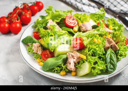 Thunfisch-Salat mit Salat, Kirschtomaten, Gurke und Mais auf betonem Hintergrund Stockfoto