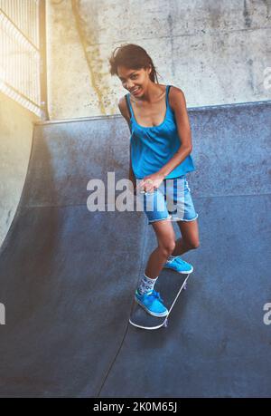 Sie glaubte, dass sie das auch tun könnte. Eine junge Frau macht Tricks auf ihrem Skateboard im Skatepark. Stockfoto