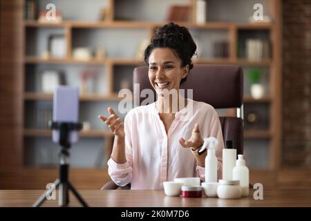 Hübsche junge Frau, Beauty Influencer, streamt von zu Hause aus und zeigt Kosmetik Stockfoto