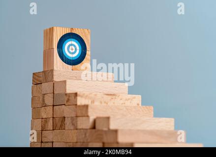 Kllose up Foto von Leiter aus Holzblöcken und Ziel-Zeichen auf der Oberseite als Symbol des Kletterns oder hart arbeiten für Ziele und Ziele. Stockfoto