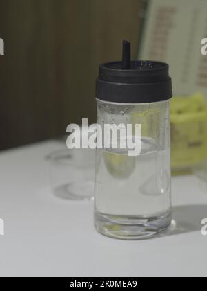 Eine vertikale Aufnahme einer Glasflasche, die halb voll Wasser ist Stockfoto
