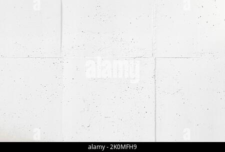 Vorderansicht einer verputzten und bemalten weißen Stein- oder Betonwand mit quadratischen Blöcken. Abstrakter, hochauflösender, strukturierter Hintergrund im Vollformat. Stockfoto