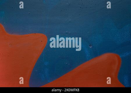 Nahaufnahme einer blau besprühten Wand mit orangen Wellenformen. Abstrakter, strukturierter Vollformat-Grunge-Graffiti-Hintergrund mit Kopierbereich. Stockfoto