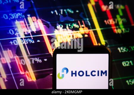 KONSKIE, POLEN - 10. September 2022: Smartphone mit Logo der Firma Holcim auf dem Hintergrund des Börsendiagramms Stockfoto