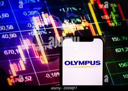 KONSKIE, POLEN - 10. September 2022: Smartphone mit Logo der Firma Olympus auf dem Hintergrund des Börsendiagramms Stockfoto