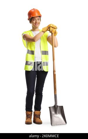Bauingenieurin mit einer Weste und einem Helm, der auf einer Schaufel auf weißem Hintergrund isoliert lehnt Stockfoto