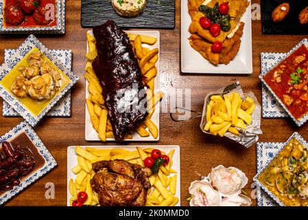 Rezepte spanischer Gerichte und Tapas mit Kroketten verschiedener Geschmacksrichtungen, Holzkohlehuhn, Cachopo, Knoblauch-Huhn, Weinwürste und gegrillten Rippchen Stockfoto