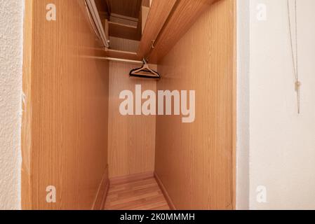 Kleiner Raum, der als Schrank mit Regalen, Hängestab und Kleiderbügeln genutzt wird Stockfoto