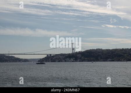 Blick auf eine Yacht, die am Bosporus vorbeifährt. Europäische Seite und FSM Brücke sind im Hintergrund. Wunderschöne Reiseszene. Stockfoto