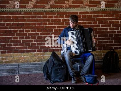 Straßenmusiker spielt Akkordeon in einer Amsterdamer Unterführung Stockfoto