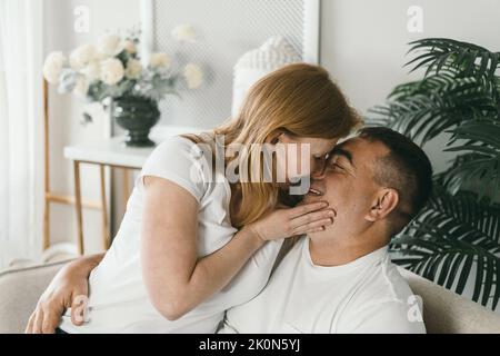 Das Ehepaar mittleren Alters umarmte sich auf der Couch. Stockfoto