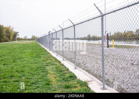 An einem regnerischen Herbsttag verläuft ein Kettenzaun entlang eines schiffbaren Kanals. Sicherheitskonzept. Stockfoto