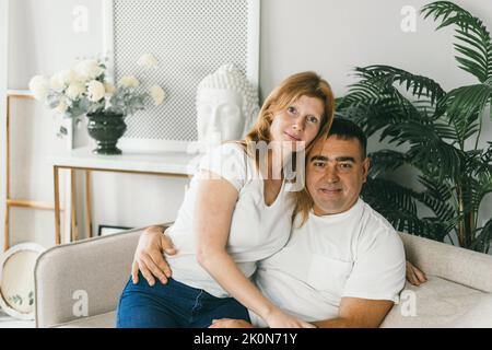 Das Ehepaar mittleren Alters umarmte sich auf der Couch. Stockfoto