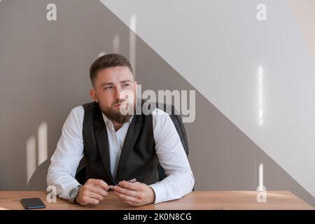 Portrait bärtiger Geschäftsmann sitzt im Büro und meditiert mit Stift in den Händen und überlegt ein Geschäftskonzept für die Zukunft. Stockfoto