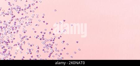 Banner mit winzigen silbernen Kristall-Konfetti auf einem rosa Pastellhintergrund. Leuchtendes Konzept mit Platz für Text. Stockfoto