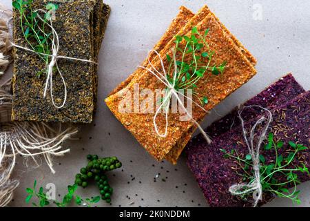 Dehydrierte fettarme glutenfreie Lebensmittel mit Micro Greens. Hergestellt aus Leinsamen und Algen, Karotten und Buchweizen, Rüben und Sonnenblumenkernen. Brot essen. Nahaufnahme. Gesundes Ernährungskonzept. Rohe Lebensmittel. Stockfoto