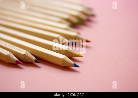 Mehrfarbige Holz geschärft Bleistiftstangen Makro Foto auf rosa Hintergrund. Werkzeuge für Kreativität, Zeichnen, Hobby, Kunstvermittlung. Zurück zum Schulkonzept. Stockfoto