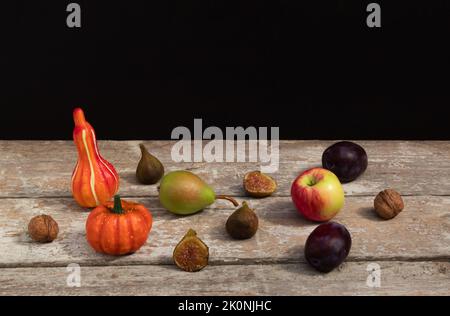 Lebensmittelzusammensetzung aus Kürbis, Kürbis und Herbstfrüchten auf altem Holztisch. Dunkler Hintergrund. Komposition im Vintage-Stil. Stockfoto