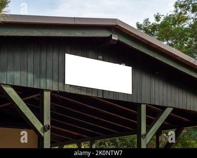 Weiße Firmenname Schild-Vorlage auf einem Holzhaus. Modell für ein Firmenlogo auf einer Außenfassade des Hauses. Gebäudefassade mit Werbung. Stockfoto