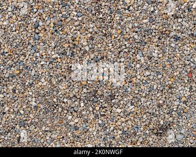 Hintergrund mit Kiesstruktur. Viele kleine Steine in verschiedenen Größen und Farben. Der Boden ist mit zufällig liegenden Objekten bedeckt. Steinmaterial. Stockfoto