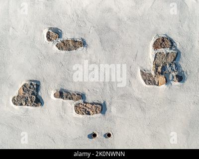 Alte Fassade mit Lücken im weißen Wandputz. Im Außenbereich des Gebäudes sind Natursteine zu sehen. Dekoration eines ländlichen Hauses. Leerer Hintergrund. Stockfoto