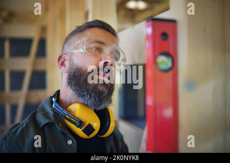 Zimmermann überprüft Holzbretter mit Wasserwaage, diy umweltfreundliche Häuser Konzept. Stockfoto