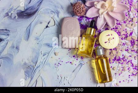 Schöne Komposition aus gelben kosmetischen Flüssigkeit Gesicht Körper ätherischen Ölflaschen, Meersalz, Seifenstücke, Lotusblume auf Pinselstrichen Oberfläche flach. Sp Stockfoto