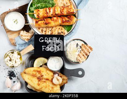 Griechischer Essenshintergrund. Meze, Gyros, Souvlaki, Fisch, Pita, griechischer Salat, Zatziki, Feta, Oliven und Fleischbällchen. Traditionell anderes griechisch Stockfoto