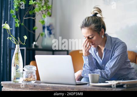 Reife professionelle asiatische Geschäftsfrau, die von zu Hause aus arbeitet, scheint frustriert und deprimiert zu sein Stockfoto