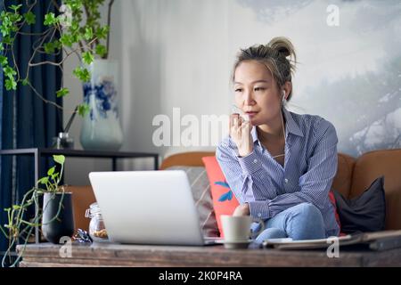 Professionelle asiatische Geschäftsfrau arbeitet von zu Hause aus Video-Chat mit Handy und Laptop-Computer Stockfoto