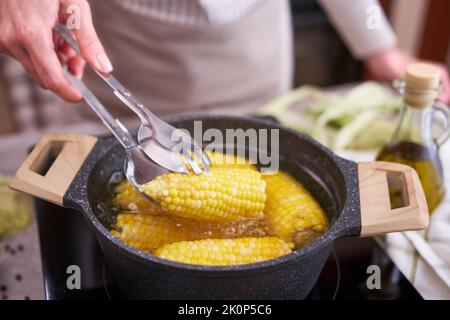 Kochen Maiskolben in einem Topf mit kochendem Wasser mit Blasen Stockfoto