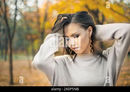 Niedliche junge gemischte Rennen Frau Mode Herbst Kleidung grau Pullover im Herbst im Freien Stockfoto