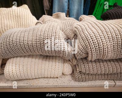 Stapeln Sie gefaltete Pullover im Bekleidungsgeschäft. Strickpullover für den kalten Herbst und Winter. Herbst-, Winter-Kleidung. Niemand, Handy-Foto Stockfoto