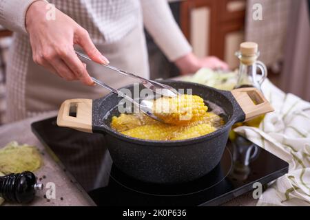 Kochen Maiskolben in einem Topf mit kochendem Wasser mit Blasen Stockfoto