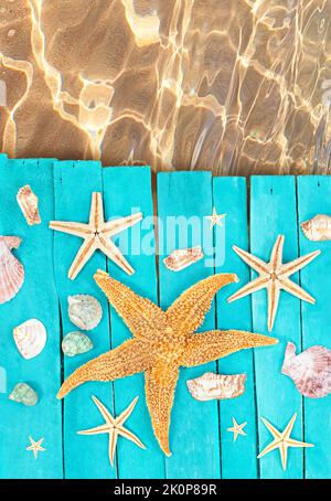 Wooden blue sea decking, boards with orange starfish, seashells near sea. Concept of vacation, tourism, summer. Copy space Stockfoto