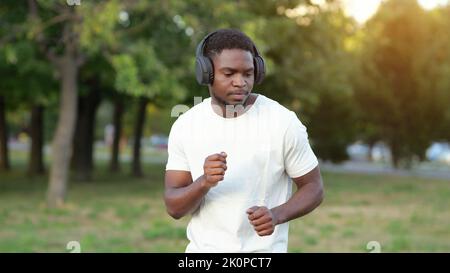 Afroamerikanischer Mann in Kopfhörern tanzt zu Musik im Park Stockfoto