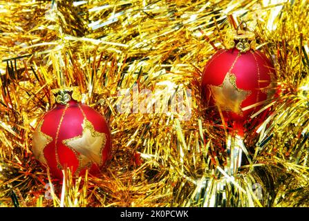 Zwei rote weihnachtskugeln auf goldener Dekoration. Stockfoto