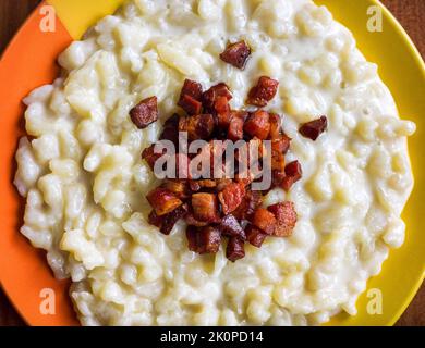 Das slowakische Nationalgericht Bryndzove halusky besteht aus kleinen Kartoffelknödeln und einer cremigen Käsesauce. Nahaufnahme Stockfoto