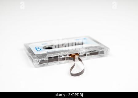 Alte Audiokassette mit losem Klebeband auf weißem Hintergrund Stockfoto