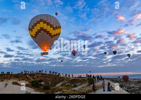 GOREME/TÜRKEI - 30. Juni 2022: Dutzende von Touristen beobachten und fotografieren das Spektakel der Heißluftballons über goreme Stockfoto