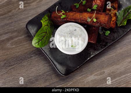 Köstliche Roggen-Knoblauchbrotcroutons mit Sahnesauce, Salz und Basilikum auf dem Teller. Junk und Fast Food für Biergetränke. Oben Stockfoto